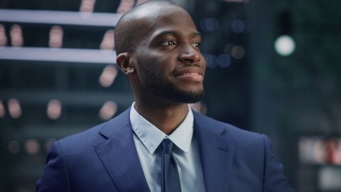Portrait of Thoughtful Black Businessman wearing Suit, Standing in the Big City Business District Street, Looking Afar at the Opportunity and Future Success. African American Digital Entrepreneur