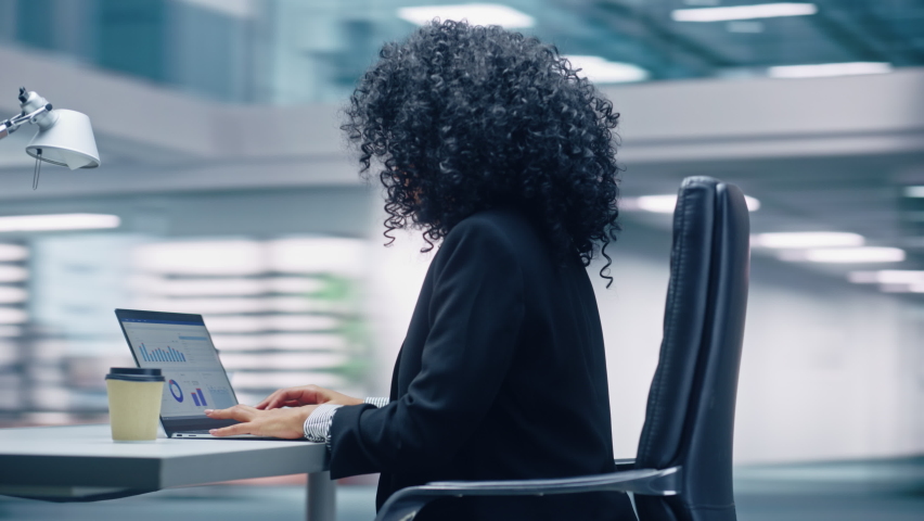 360 Degree Office: Black Businesswoman Sitting at Her Desk Working on a Laptop Computer. Smiling Successful African American Woman working with Big Data e-Commerce. Moving Around Tracking Shot Royalty-Free Stock Footage #1082482282