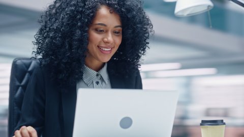 360 Degree Office: Black Businesswoman Sitting at Her Desk Working on a Laptop Computer. Successful African American Woman working with Big Data e-Commerce. Hands to Face Moving Around Tracking Shot