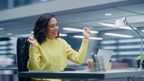 360 Degree Office: Smiling Hispanic Businesswoman Sitting at Desk Working on Computer, Dances while Listening Music. Latin Female Entrepreneur is Happy, Joyful, having Fun. Moving Around Tracking Shot