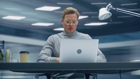 Modern Office: Handsome Businessman Sitting at His Desk Working on a Laptop Computer. Man working with Big Data e-Commerce Analysis. Energetic 360 Degree Fast Tracking Shot. Camera Moving Around