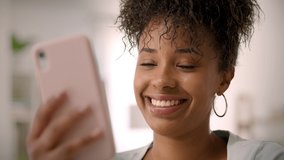 Slow Motion Happy African American Young Woman Using SmartphoneThinking and Laughing. Video Conference, Friends Chatting, Online Learning or Teleworking. Millennial Authentic Real Female Portrait.