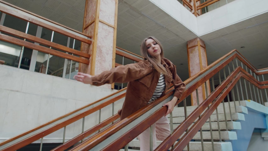 Young confident woman, dancer, is training on stairs, holding on balustrade and practicing different movements, working persistently to master contemp dancing style, Slow motion.