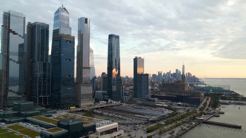 Aerial view of the New York City waterfront skyline, buildings in Hudson Yards, the river, sunset and Jersey cityscape - pan, drone shot