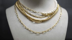 Golden necklace chain with white pearls close-up in light. Luxurious expensive beautiful accessory hanging on holder in jewellery store. Slow motion - Powered by Shutterstock - Get 15% off with code: PIKWIZARD15