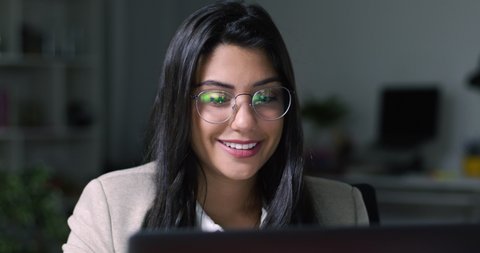 Lateral Dolly of Young Caucasian Focused Businesswoman in Eye Glasses Late at Night Working in Front of Computer. Financial Animations.