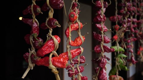 Red peppers are hung and dried under the eaves of the house. Green and deep red colors. Asian spices tied with dried straw. Rotating gimbal shot