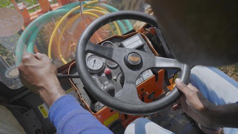 close up shot of the hand of a young worker moving steering wheel of the pest control, pesticide, or fertilizer agriculture machine or vehicle. tracking detail shot with shallow depth of field