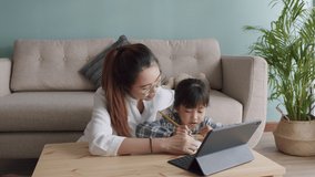 Asian family with daughter doing homework by using tablet with mother help. Asia student little girl learning with parent, Concept of online learning at home 