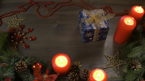 Christmas gift, top-down view. Female hands put a box with a gift on a table decorated with branches of a Christmas tree