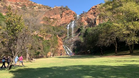 Krugersdorp, South Africa - 22nd June 2021: Water fall at National Botanical Garden with tourists walking.