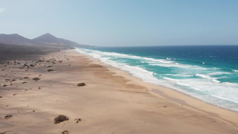 Aerial view of Cofete beach with endless horizon and traces on the sand. Volcanic hills in the background and Atlantic Ocean. Cofete beach, Fuerteventura, Canary Islands, Spain.
