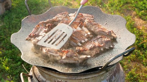 Close-up of goat meat fried on a fire. Grilled sheep ribs. Goat meat is fried in a pan outdoors. selective focus. lamb meat with bones cooking