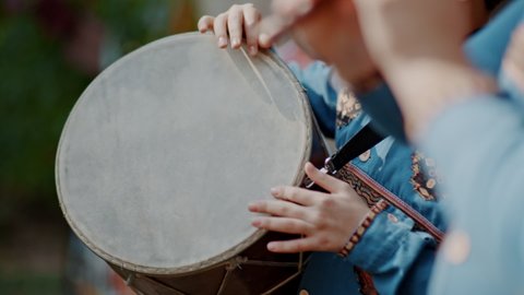 Armenian boy drummer's hands playing dhol drum in traditional armenian wear during the harvest festival