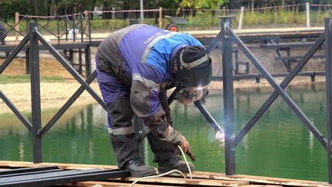 MOSCOW, RUSSIA - SEPTEMBER 20, 2021: Manual Metal Arc Welding of the pond fencing in a park.