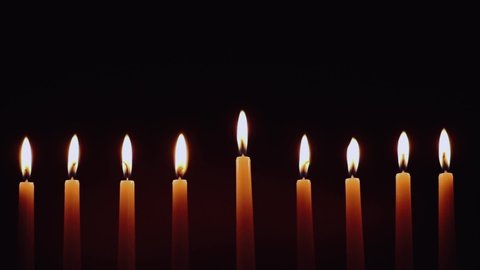 Hanukkah candles. Traditional candelabrum with burning candles on black background. Celebrating a religious Jewish holiday.