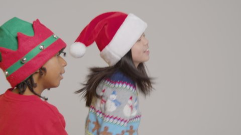 Two boys in Festive outfits dance around, against a grey background.