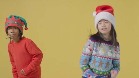 Two boys in Festive outfits dance around, against an orange background.
