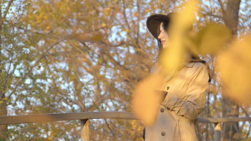 White girl (20 years old) in a black hat and gray coat walks in the autumn park