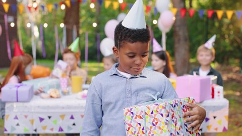 Happy birthday multiracial kid looking at the camera with unwrapped birthday present. Boy is exited to open birthday gift. Birthday celebration concept