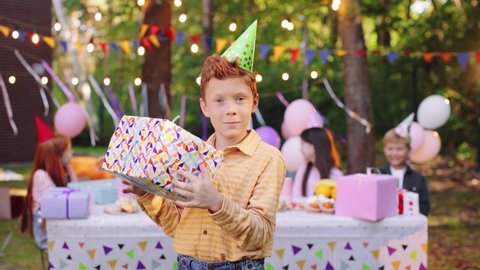 Happy birthday caucasian kid shaking unwrapped birthday present. Boy is exited to open birthday gift. Birthday celebration concept
