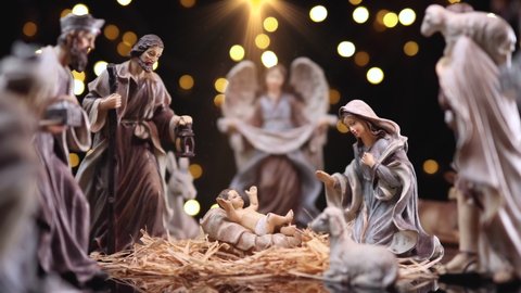 Jesus Christ Nativity scene with atmospheric lights. Jesus Christ Nativity scene with figurines and light particles. Christmas scene. Dolly shot 4k
