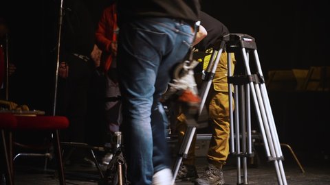 Ukraine, Chernivtsi - November 15, 2021: Filming. The camera crew is busy preparing for the shoot and moving the camera from the tripod to the floor to change frame. Actors are sitting in background