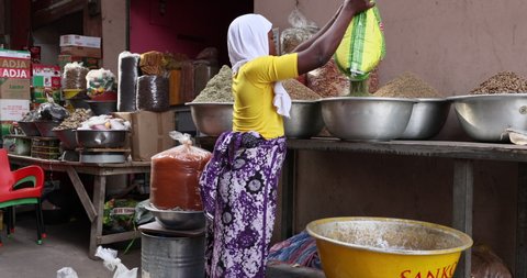 NIMA, GHANA - 30 SEP 2021: Muslim woman seed grain market Accra Ghana part 2. Historical busy congested market area downtown, Accra, Ghana. Historic place to buy and sell products, food.