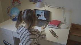 Preschooler girl, a child with a teacher learning letters online on a laptop, distance learning online, talking to a camera at a virtual video conference lesson at home