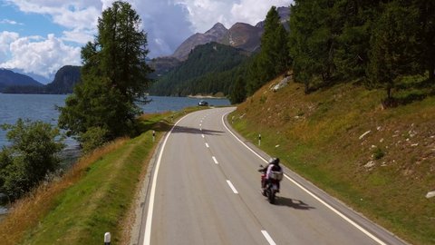 Aerial drone footage of motorcycles driving along the lake Sils in the Engadine valley in Canton Graubunden in the alps in Switzerland