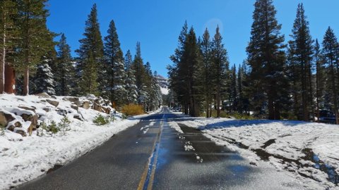 Slushy snow covered open road, in snowy Mammoth lakes in sunny California with clear blue sky - static view