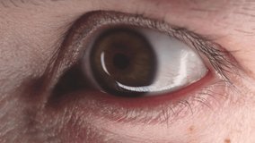 Detailed macro video of a hazel eye. Close-up shot of a young caucasian man looking at the camera. Concept of focus, concentration and health care.
