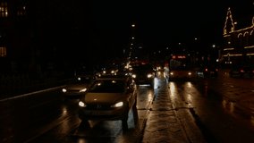 Blurred video of traffic in rainy evening city with lights reflecting in the streets. Cars and bicycles with headlights and lights on in night city. Background movie for copy text.  