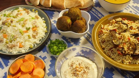 Arabian cuisine. Bulgur with eggplant, falafel, bean soup on table, couscous with chicken. Traditional middle eastern culture. Moutabal and vegetable salad in bowls, pita. Delicious rice with meat.