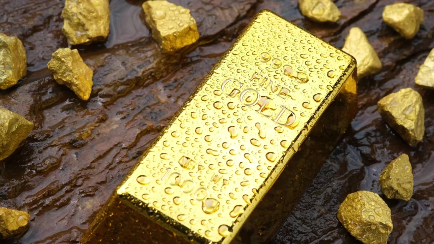 Gold bars with water droplets rested on the rocky ground and the gold ore from the mines lay around. and water was poured out to wash off the water droplets that looked like beautiful gold.