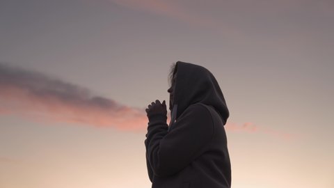 Girl praying on a pink sky background, believe in good good, ask for help, dream looking up, motivation inspiration outdoors, woman thinks meditating, wanderlust concept, heavenly light