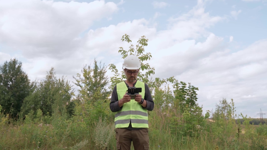 An electrical engineer in a white helmet inspects the poles and power lines.