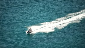 Aerial drone video of watercraft scooter making extreme manoeuvres, while cruising in high speed over deep blue open sea ocean