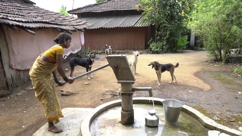 Indian woman using hand water pump, Maharashtra, Palghar, India, Circa 2021