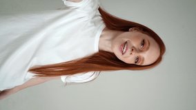 Vertical POV portrait of cheerful young woman talking via video chat using mobile phone looking at camera, on white isolated background in studio. Point of view of happy lady talking to camera.