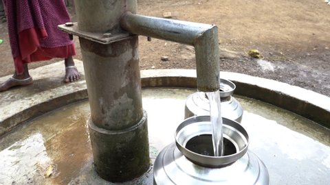 Filling metal container with drinking water from hand pump, India