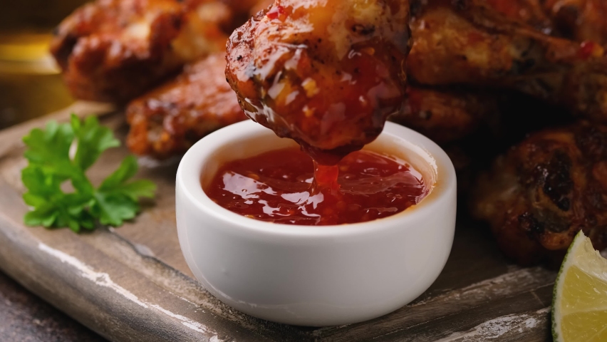 Dipping buffalo chicken wings in sweet chili sauce. fast food. Royalty-Free Stock Footage #1082587870