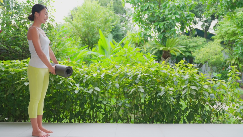 Young woman doing meditation exercise stretching sports, white tank top and yellow Legging, Female practicing yoga, natural balance between body and mental development. With bautiful green garden.