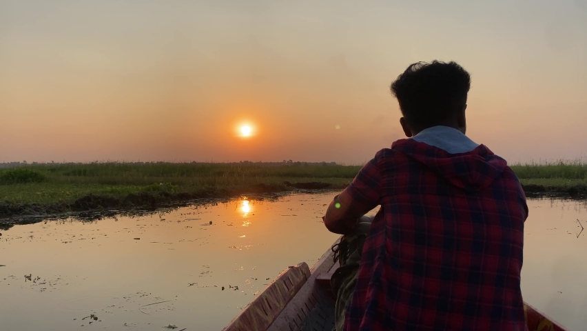 Silhoutte of a man sitting on bow of boat watching sunrise peacefully, slow motion. Shot in 4k.