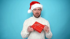 This video is about disappointed man holding red gift box isolated on blue background