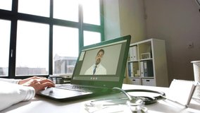 healthcare, technology and medicine concept - female doctor in white coat with laptop computer having video call with indian male colleague at hospital