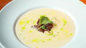 Stock food video with cream soup with boiled beef meat and olive oil cooked for lunch in restaurant