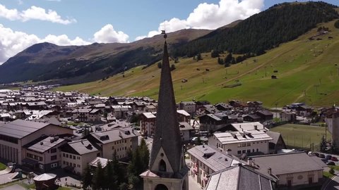 Full Hd raw aerial footage of a orbit around a bell tower roof in Livigno, one of the most iconic town in the alps