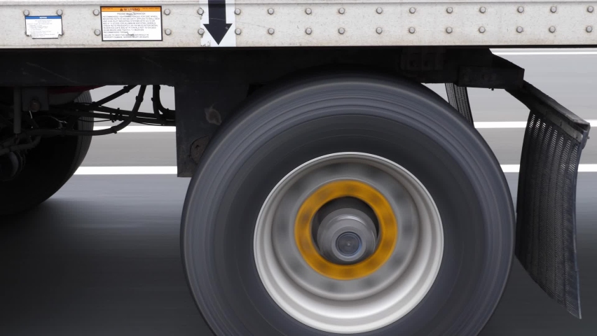 Passing commercial truck or lorry. Detail of wheels with yellow hubs. Highway driving in Ontario, Canada. Royalty-Free Stock Footage #1082599909