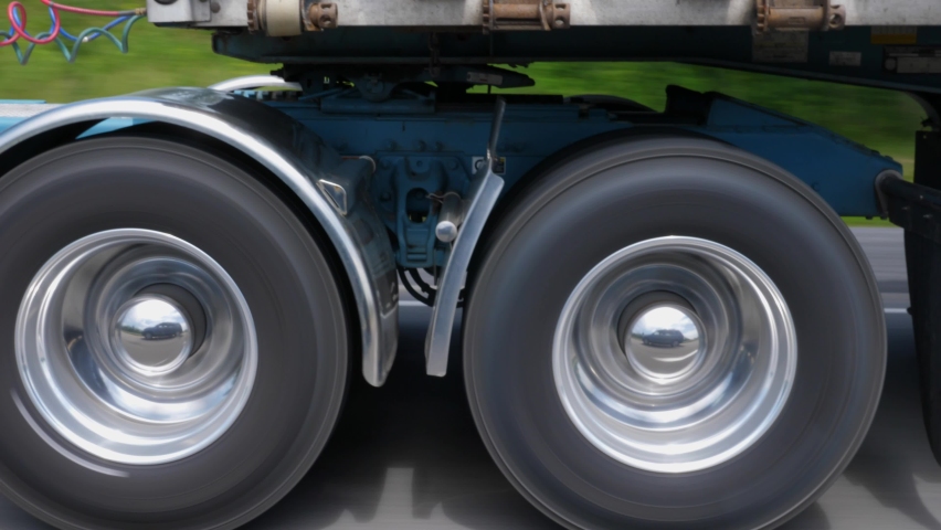 Driving beside commercial tractor trailer. Detail of chome wheels and trailer hitch. Highway driving in Ontario, Canada. Royalty-Free Stock Footage #1082599921